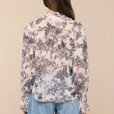 Person wearing a floral blouse and blue jeans on a beige background
