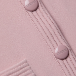 Close-up of a pink textured fabric with buttons and visible branding.