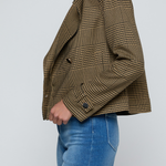 Model wearing a printed trench jacket with jeans on an off white background.
