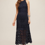 woman in navy lace midi dress on tan background 