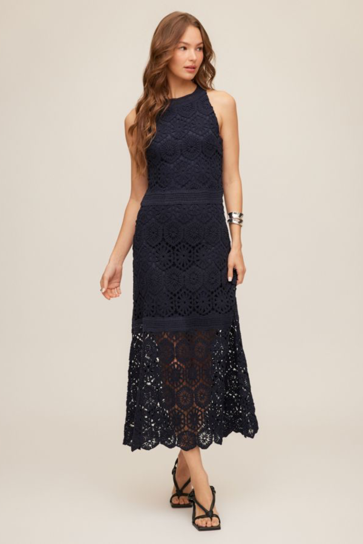 woman in navy lace midi dress on tan background 