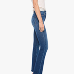 A woman shown in side profile wearing blue flare jeans, a light beige sleeveless top, and gray heeled sandals against a plain light gray studio background.