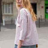 Woman wearing a striped shirt and jeans on a street with a blurred background