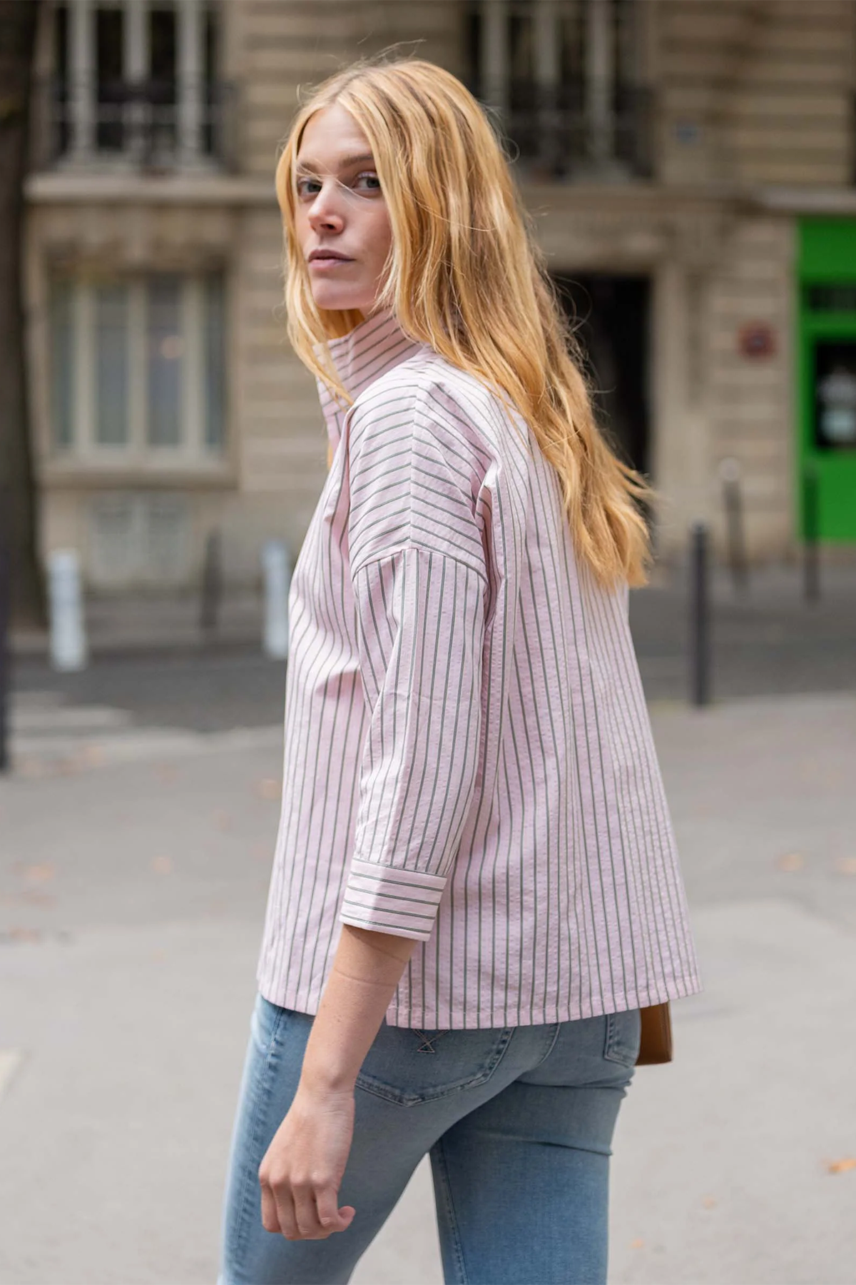 Woman wearing a striped shirt and jeans on a street with a blurred background