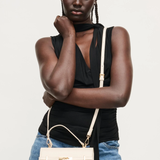 Woman holding a beige handbag against a white background