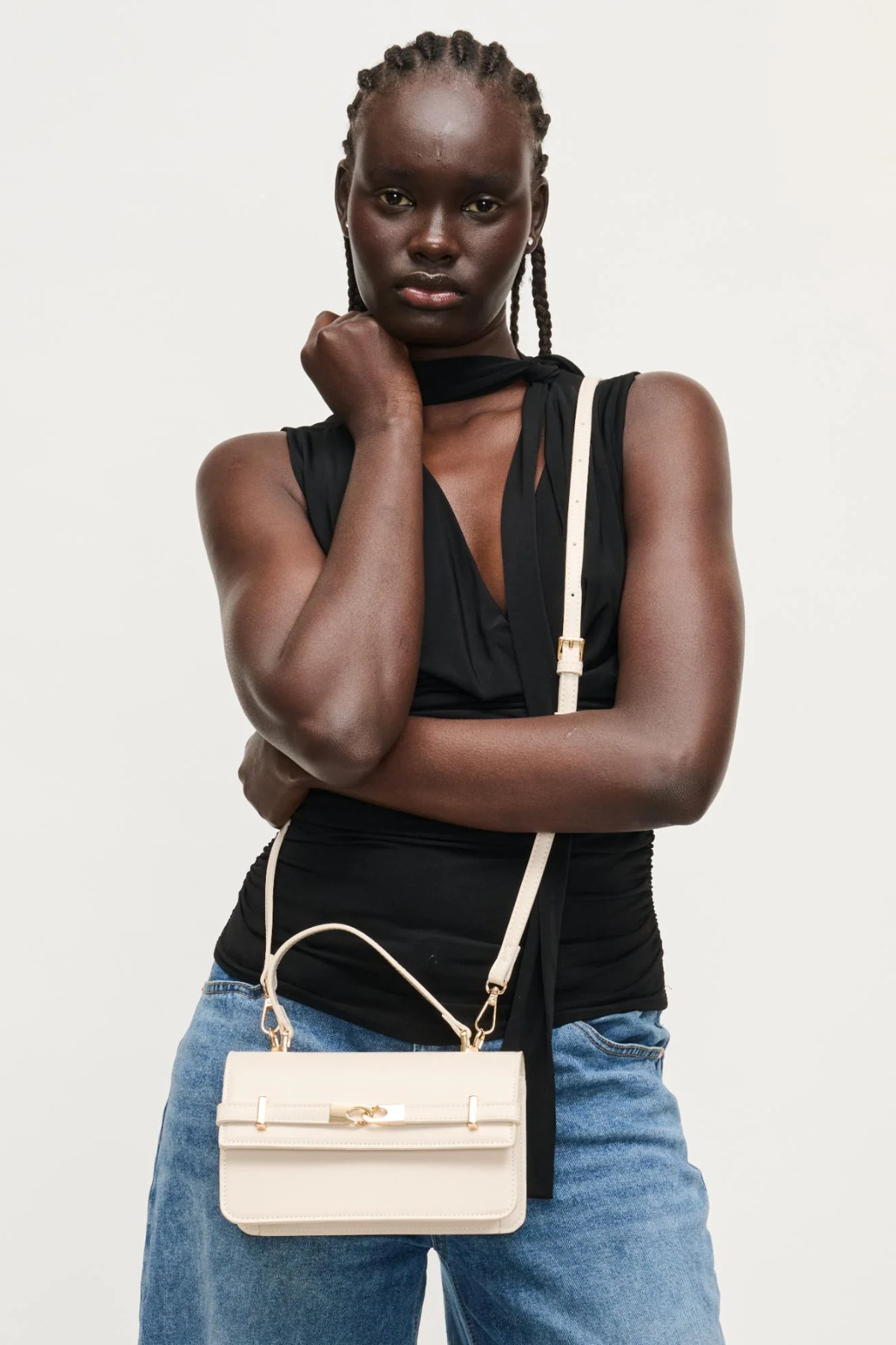 Woman holding a beige handbag against a white background