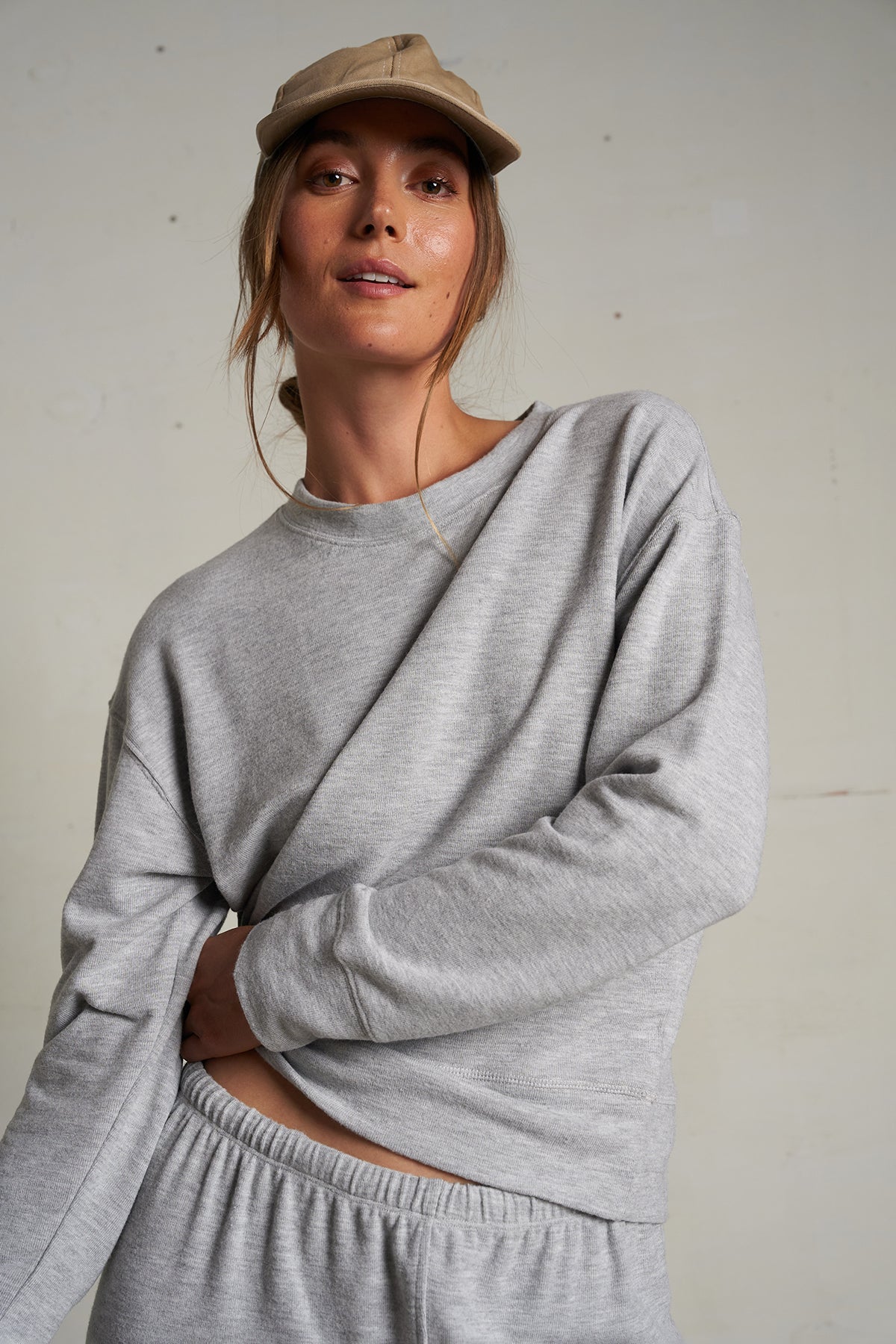 Woman wearing a light grey long-sleeve knit top with a relaxed fit, photographed against a soft neutral backdrop.