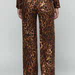 A person shown from the back wearing leopard-print trousers and a matching long-sleeve top against a light gray studio background.