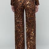 A person shown from the back wearing leopard-print trousers and a matching long-sleeve top against a light gray studio background.