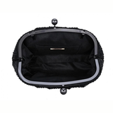 The interior view of a black textured clutch handbag with a black satin lining, a silver-tone metal frame, and pearl-like clasp details on a white background.