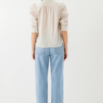 Person wearing a light-colored shirt and blue jeans on a white background