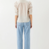 Person wearing a light-colored shirt and blue jeans on a white background