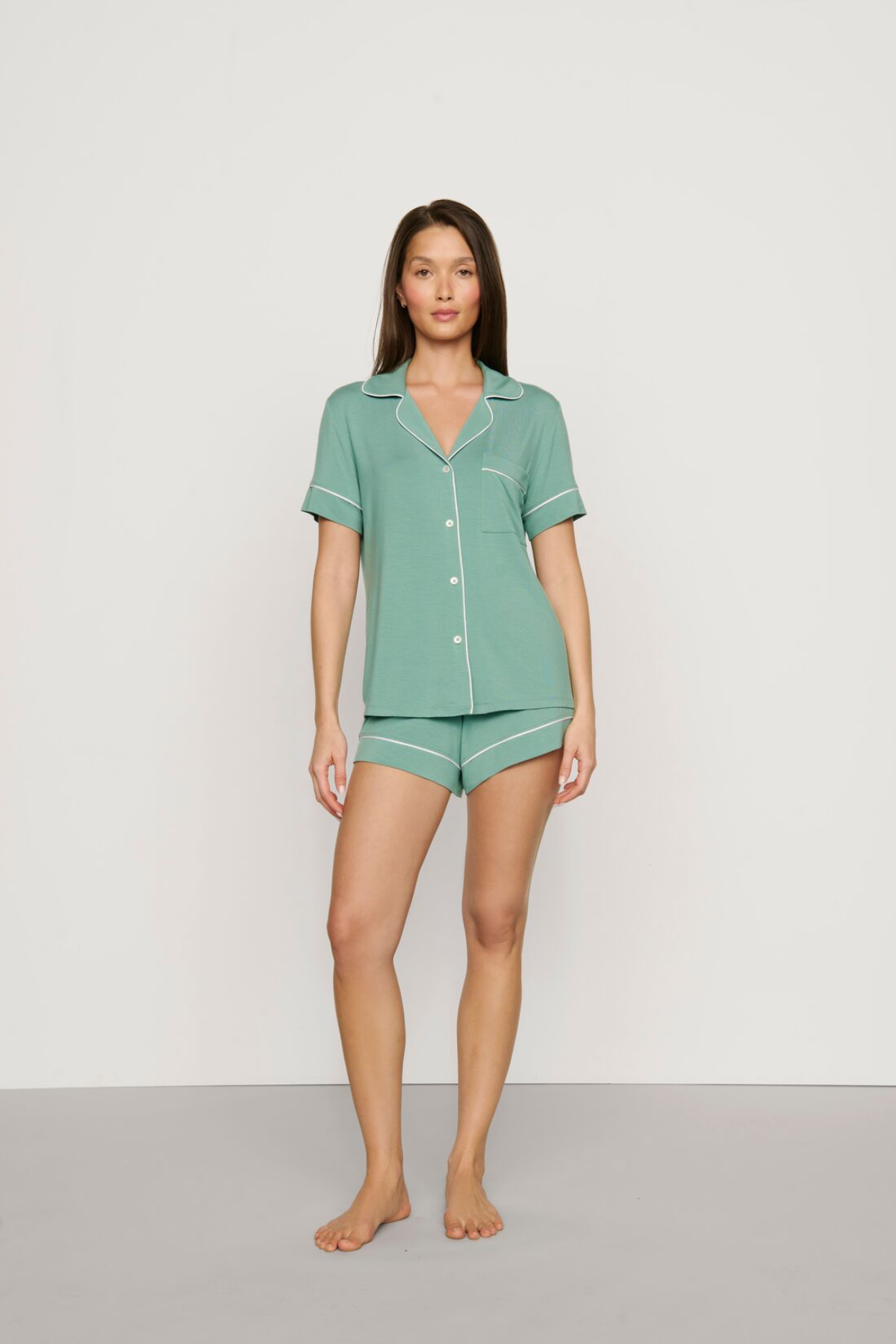 Woman wearing a green pajama set against a white background
