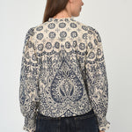 Woman wearing a patterned long sleeve blouse with a gathered neckline in neutral tones