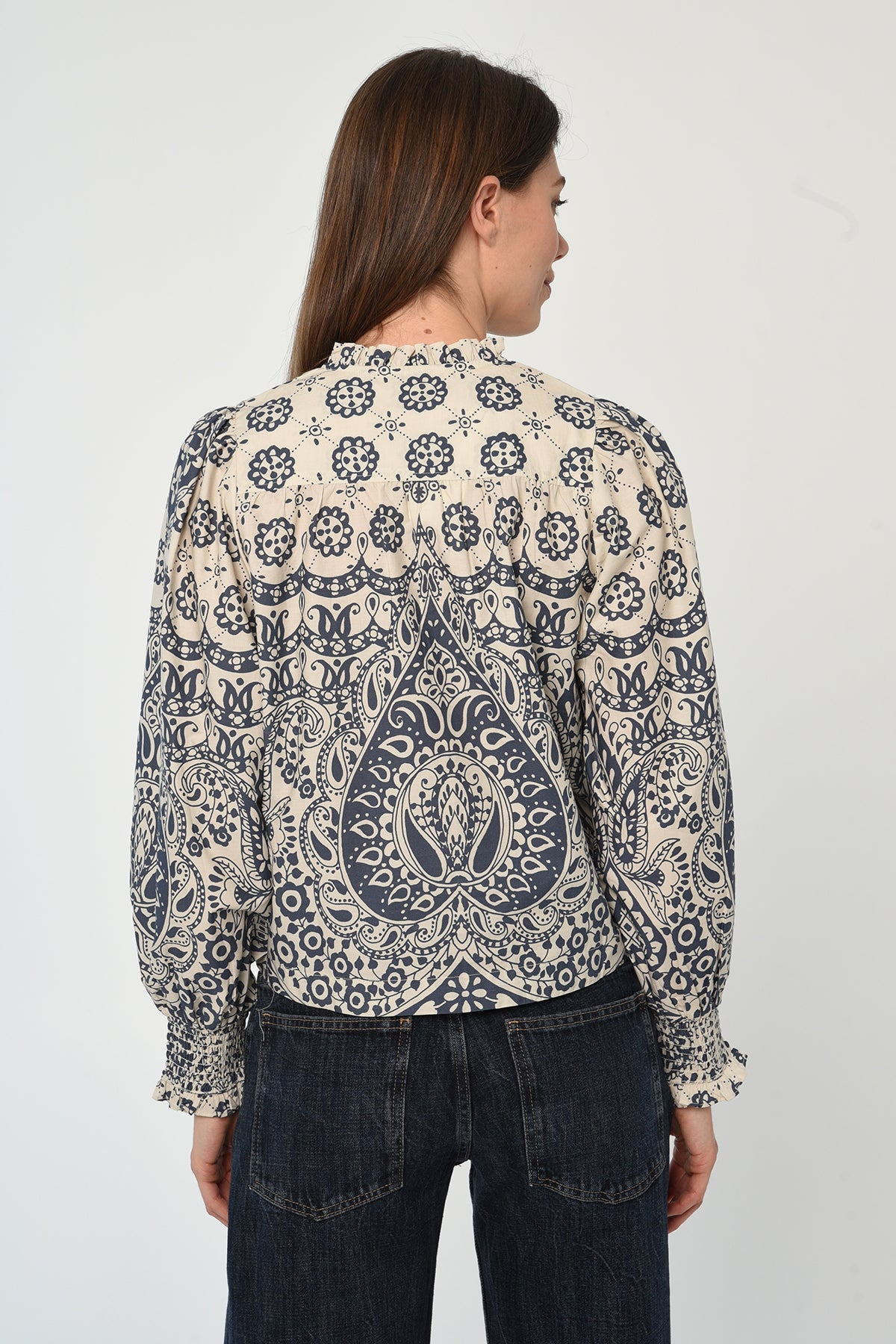 Woman wearing a patterned long sleeve blouse with a gathered neckline in neutral tones