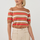 Woman wearing a brown, red, and white striped shirt with beige pants on a light gray background