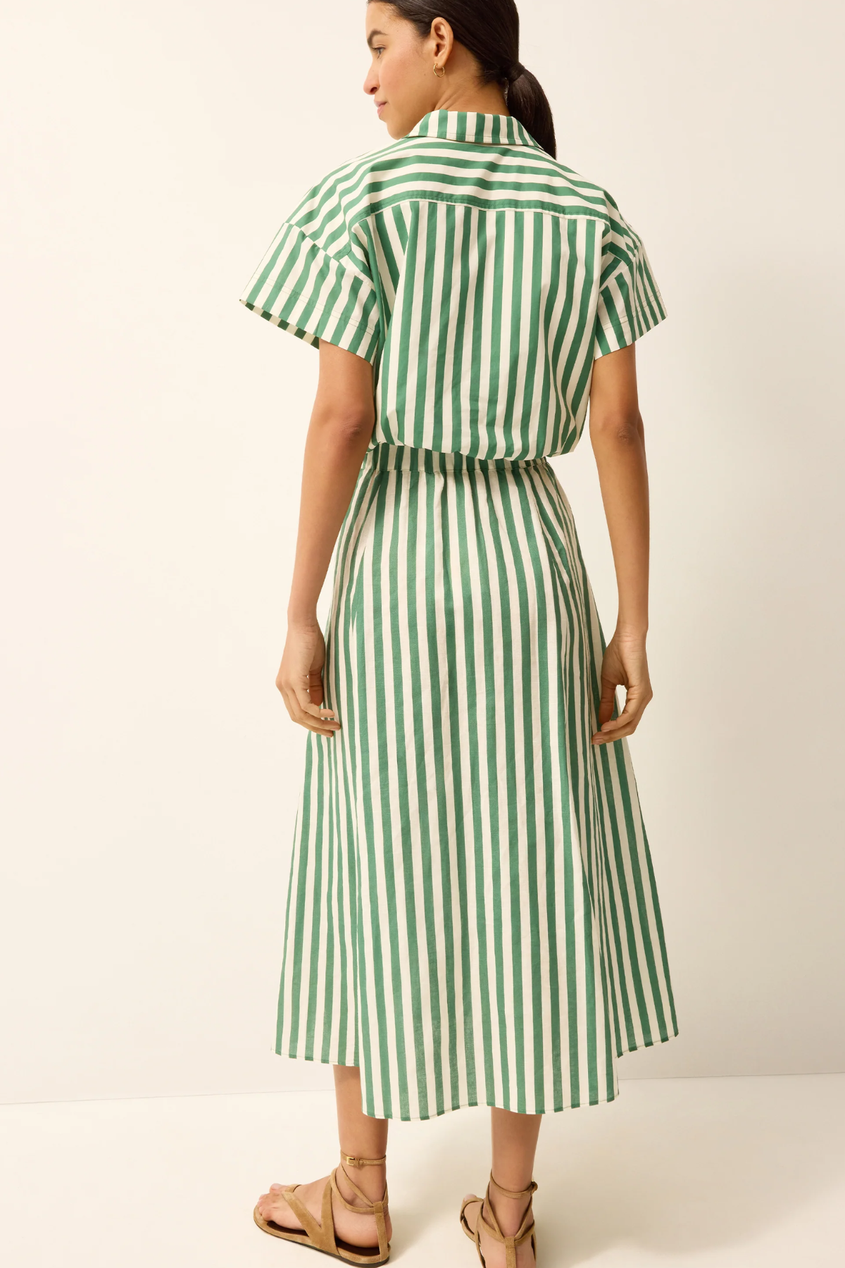 Woman wearing a green and white striped skirt on a plain background