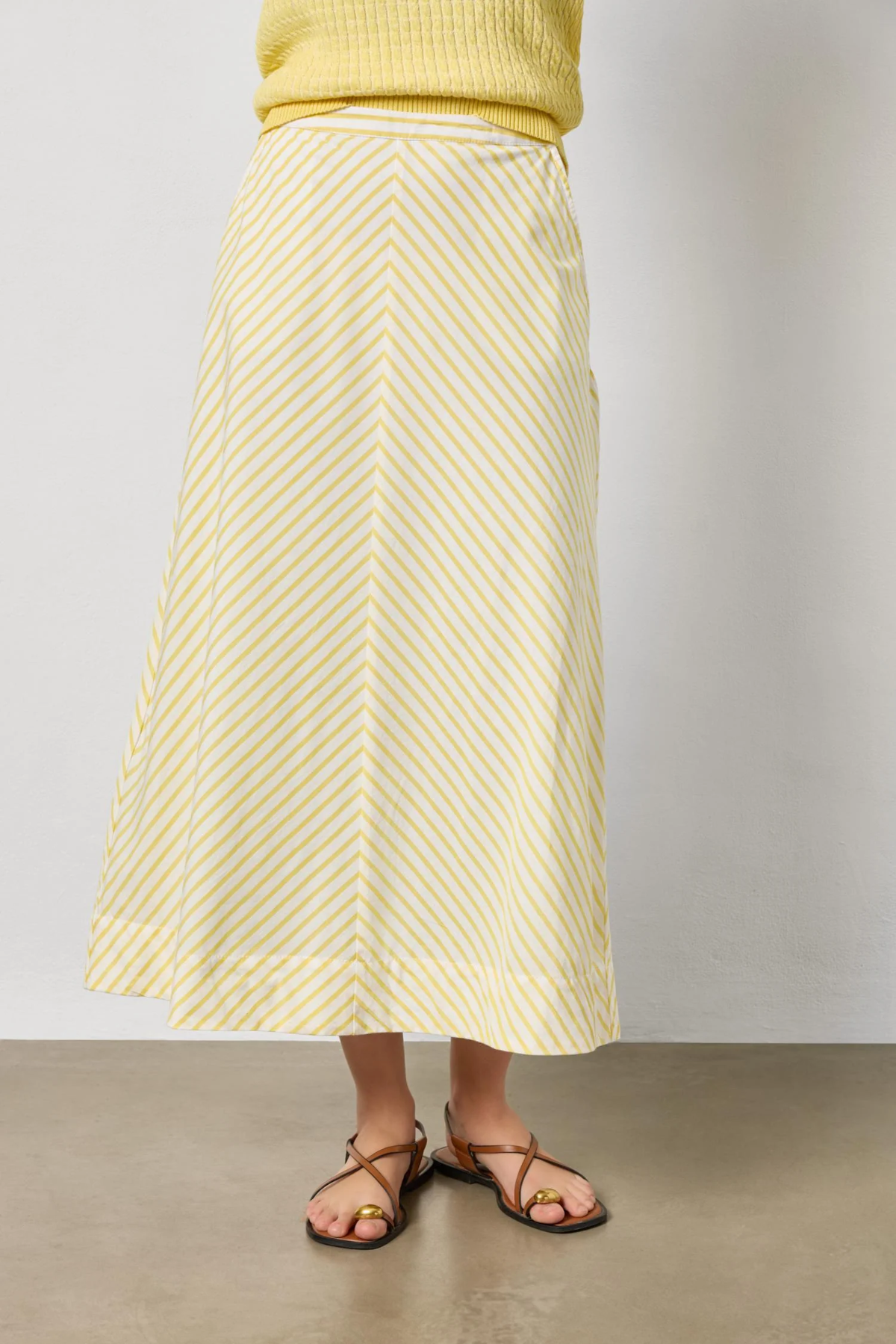 Person wearing a yellow and white striped skirt against a plain background