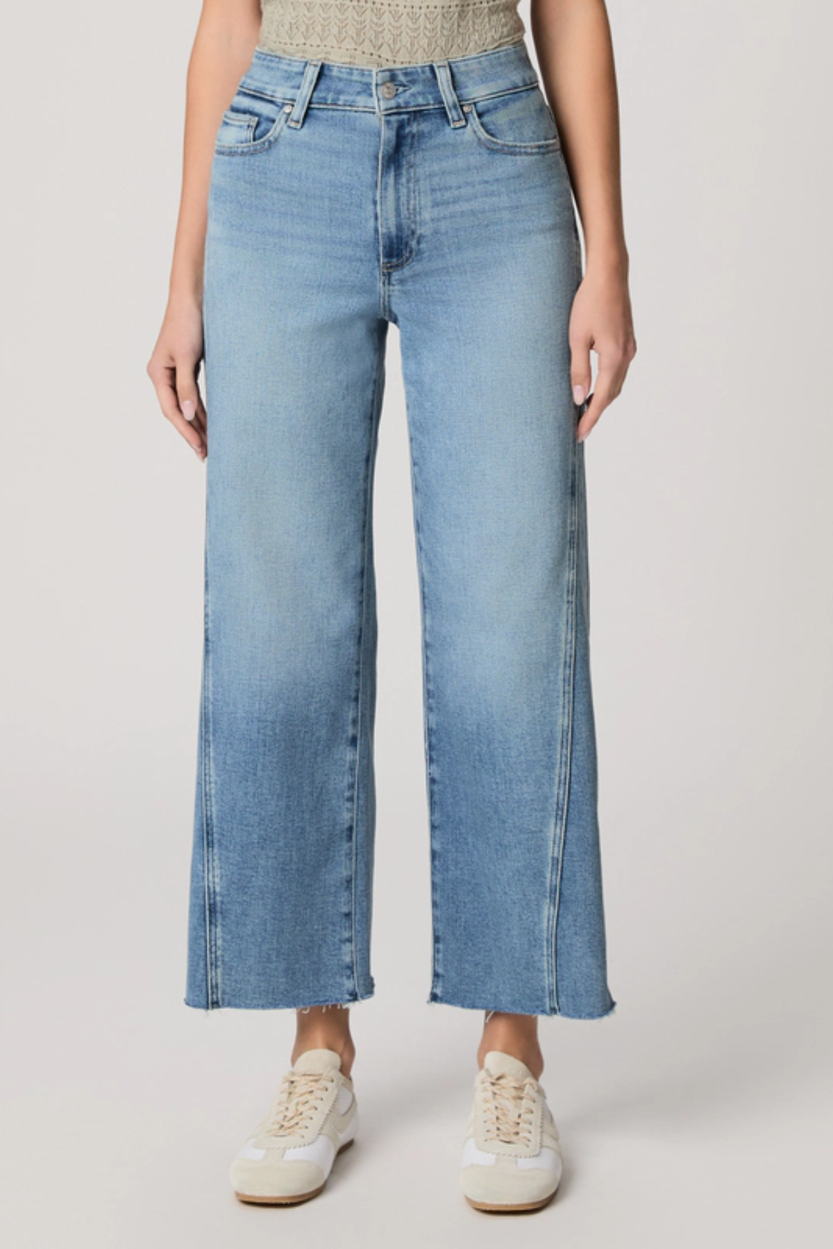 Person wearing light blue jeans on a plain background