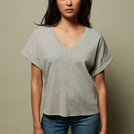Woman wearing a gray oversized t-shirt and blue jeans against a beige background