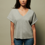 Woman wearing a gray oversized t-shirt and blue jeans against a beige background