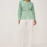 Woman wearing a green and white striped shirt with white pants on a white background