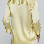 Yellow satin shirt worn by a person on a plain background