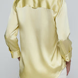 Yellow satin shirt worn by a person on a plain background