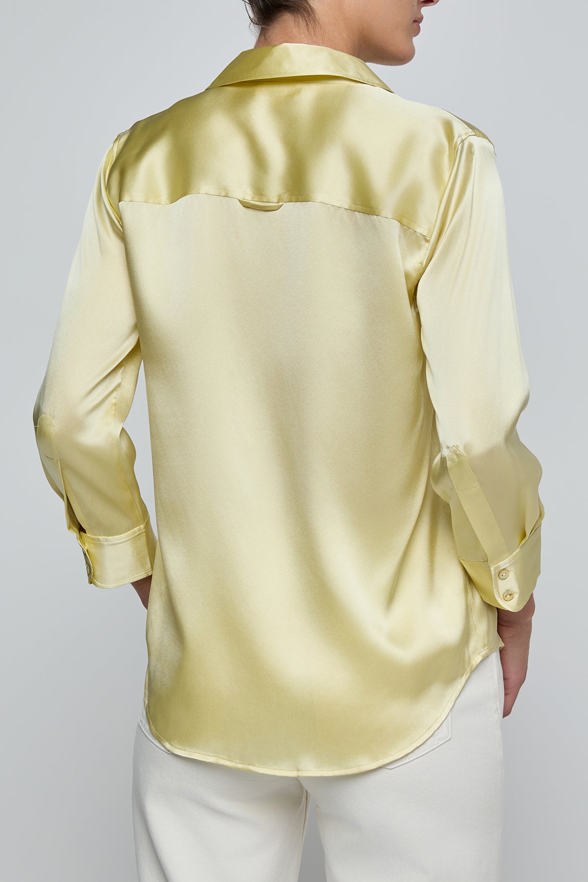 Yellow satin shirt worn by a person on a plain background