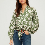Woman wearing a green floral blouse and blue jeans on a white background