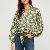 Woman wearing a green floral blouse and blue jeans on a white background