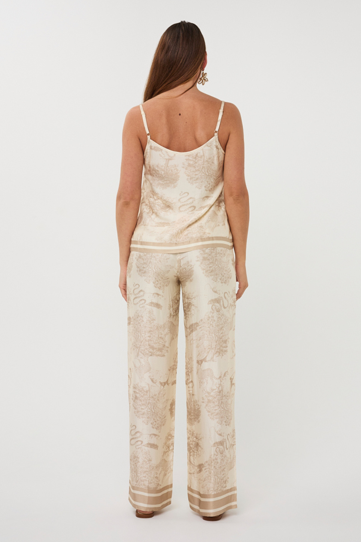 Woman wearing a beige patterned jumpsuit on a white background