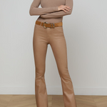 Woman wearing a beige long-sleeve top and pants with a belt on a plain background