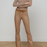 Woman wearing a beige long-sleeve top and pants with a belt on a plain background
