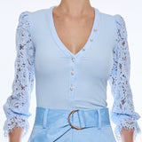 woman in light blue blouse with lace sleeves 