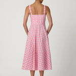 back of woman in pink gingham dress on white background 