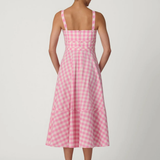 back of woman in pink gingham dress on white background 