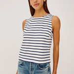 Woman wearing a striped tank top and jeans against a plain background