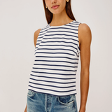 Woman wearing a striped tank top and jeans against a plain background