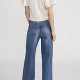 Person wearing a white top and blue jeans on a plain background