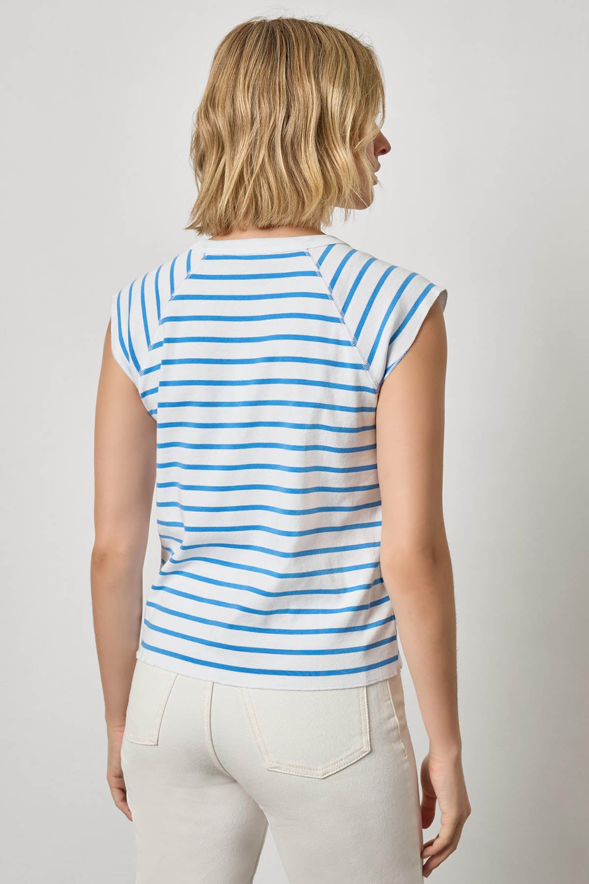 Woman wearing a blue and white striped sleeveless top against a plain background