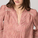 Woman wearing a pink floral blouse against a plain background