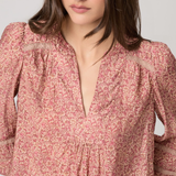 Woman wearing a pink floral blouse against a plain background