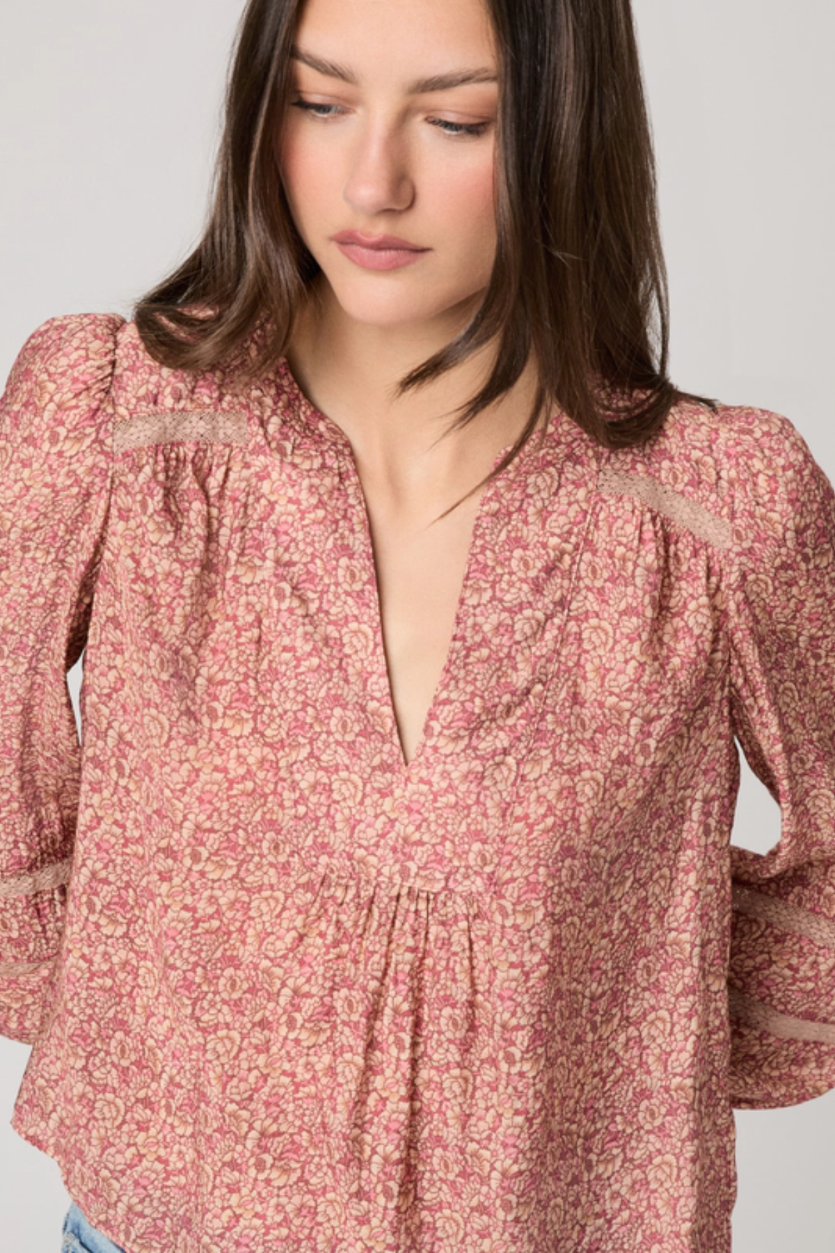Woman wearing a pink floral blouse against a plain background