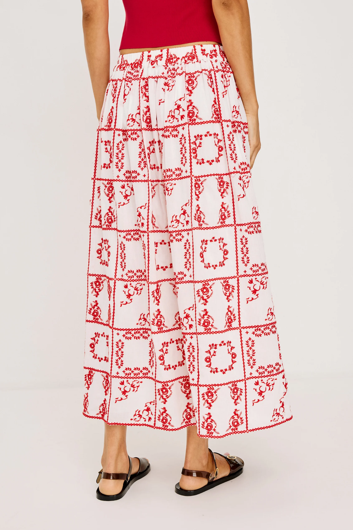 Person wearing a red and white patterned skirt on a plain background