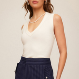 woman in white tank and pearls on tan background 