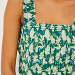 Green and white floral patterned top on a person against a white background