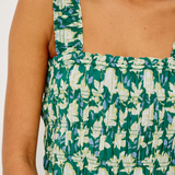 Green and white floral patterned top on a person against a white background