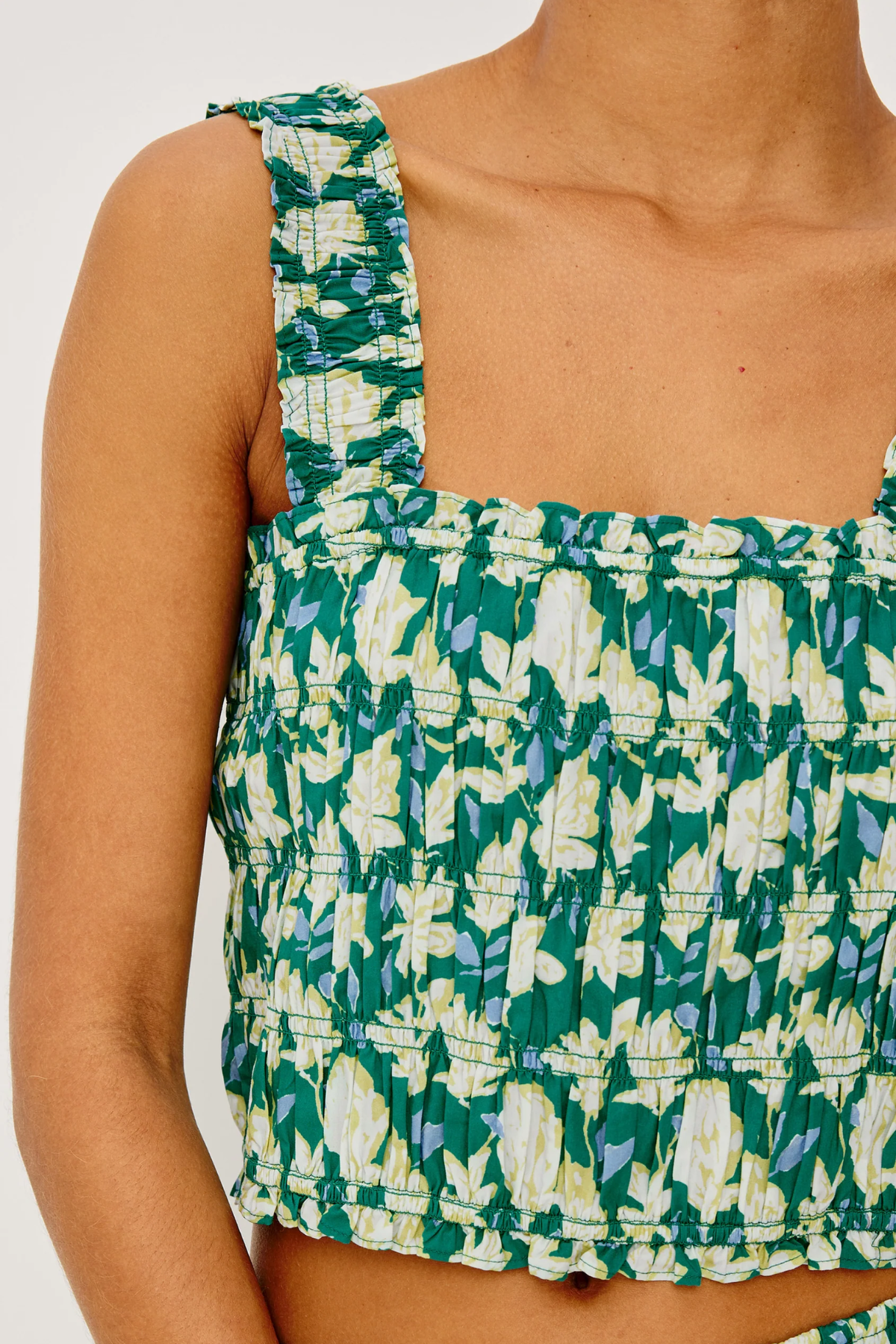 Green and white floral patterned top on a person against a white background