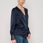 Model wearing a long-sleeve blouse with delicate lace detailing and a flattering tailored silhouette.